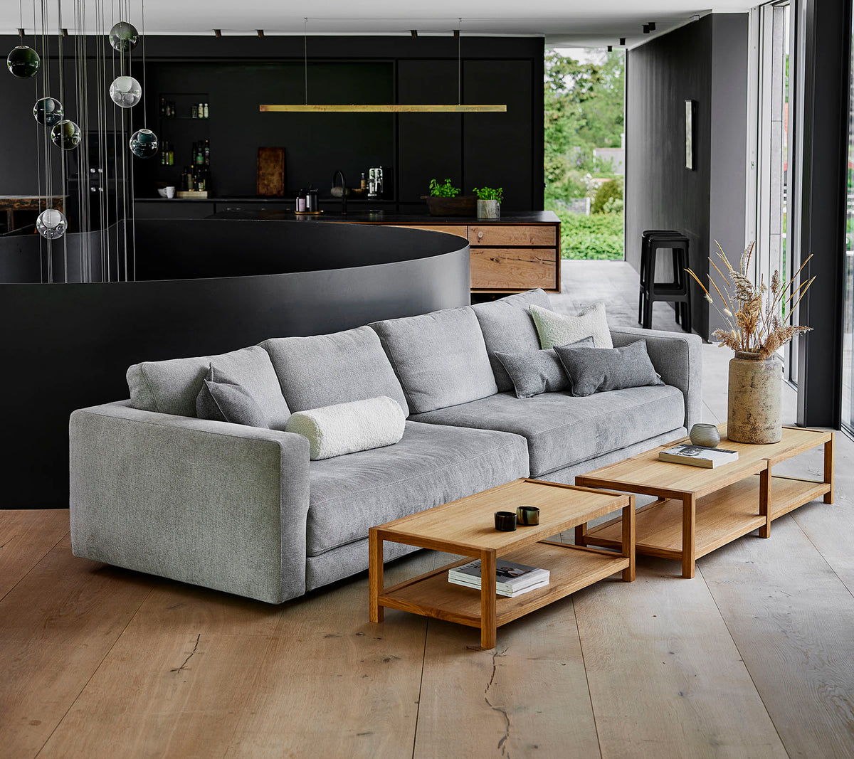 A modern, gray sofa with plush cushions alongside wooden coffee tables in a contemporary setting with stylish decor.