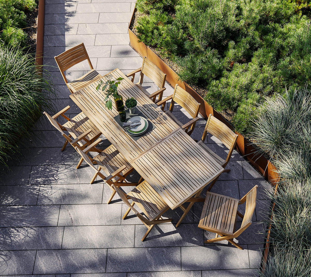 A spacious wooden dining table surrounded by matching chairs, adorned with a centerpiece and framed by lush greenery.