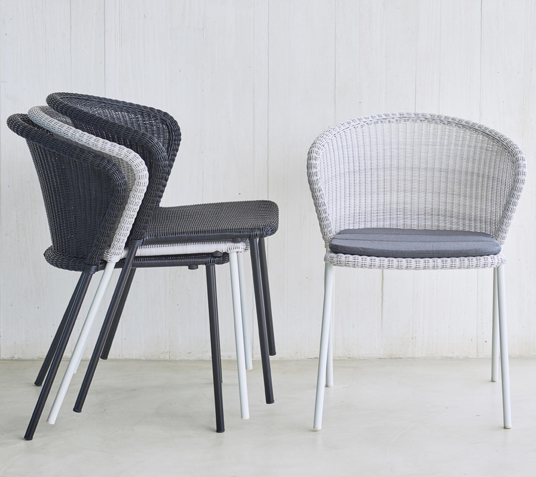Stack of modern, woven chairs in black and white, featuring a cushioned seat, ideal for stylish seating solutions.
