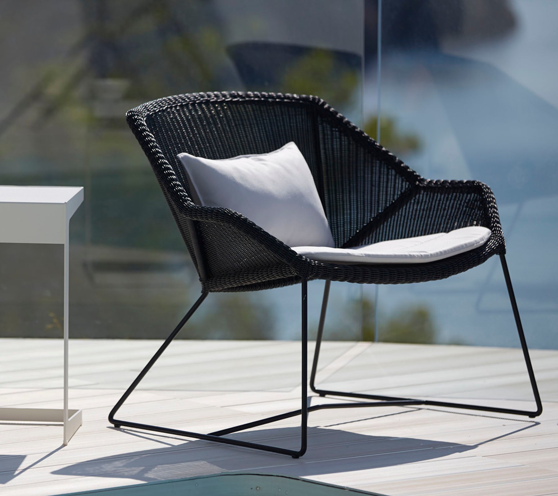 Modern black chair with white cushion in a stylish outdoor lounge setting.
