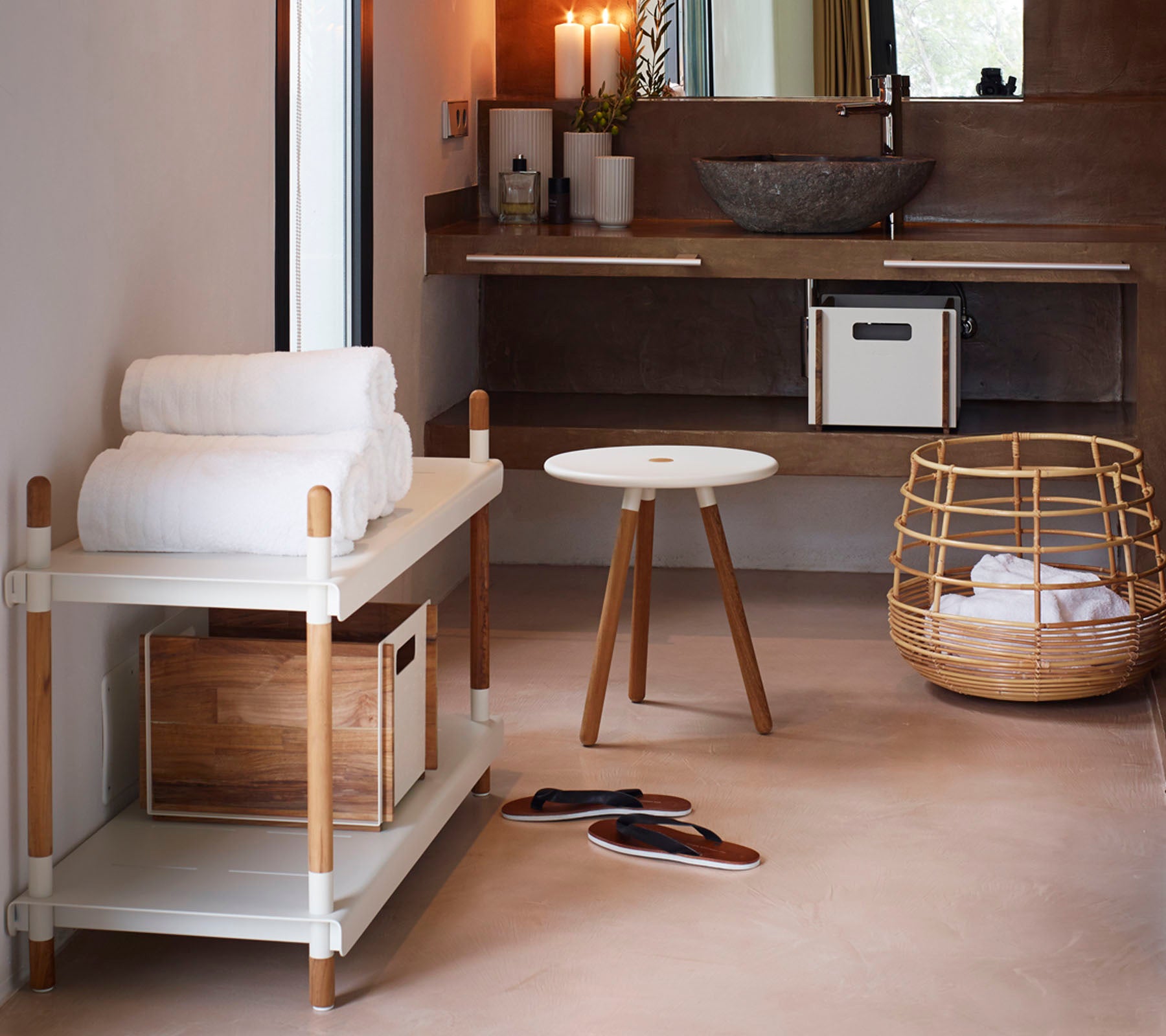 A minimalist space featuring a towel rack with folded towels, a small round table, and a wicker basket, creating a cozy atmosphere.