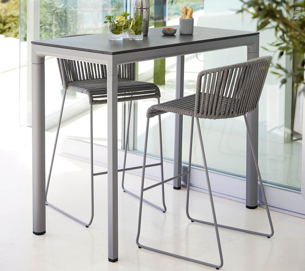 A modern table with a sleek surface accompanied by two stylish, high-backed chairs, ideal for casual dining or gatherings.