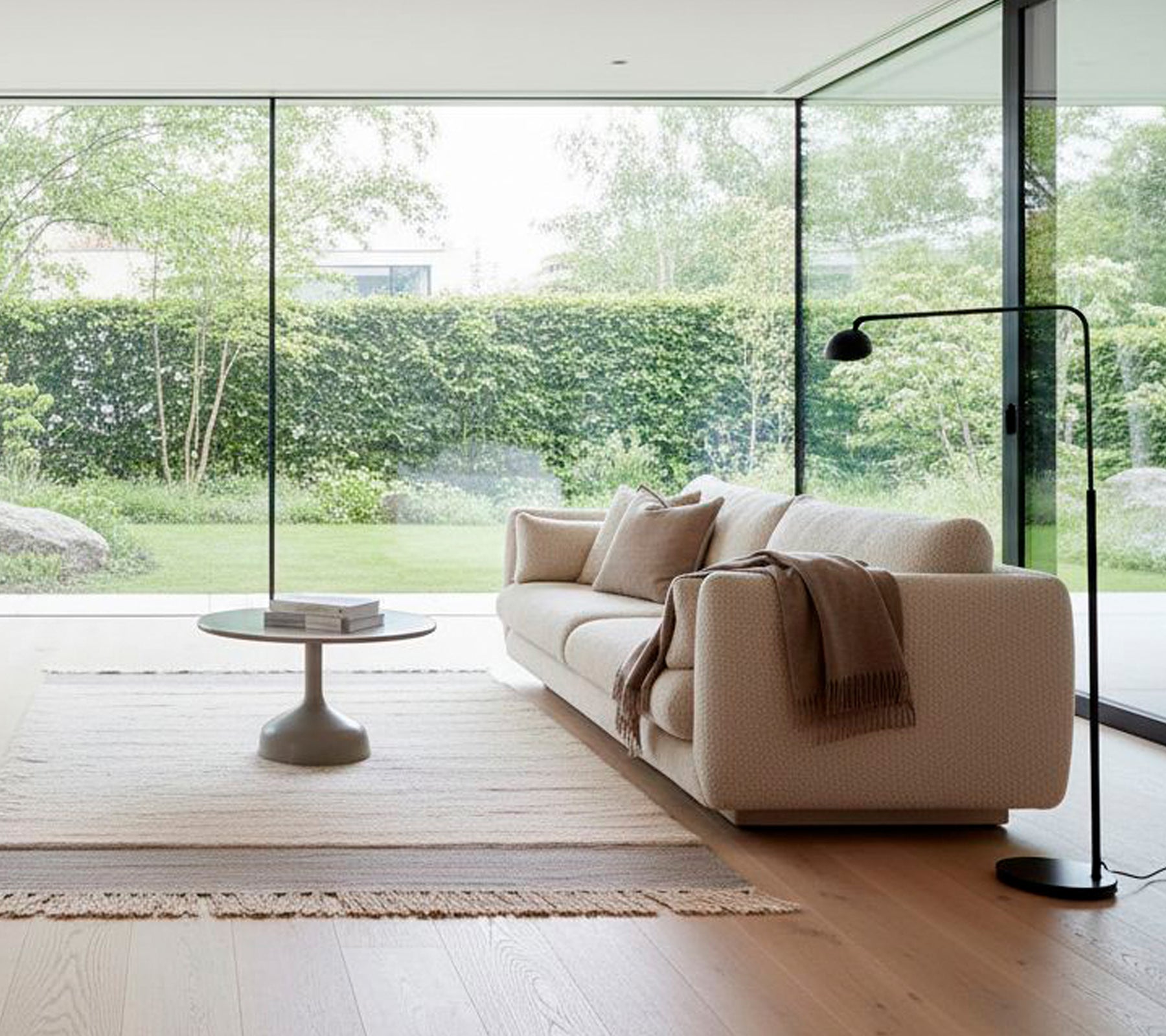 Modern white sofa with a black floor lamp and round coffee table in a minimalist lounge.