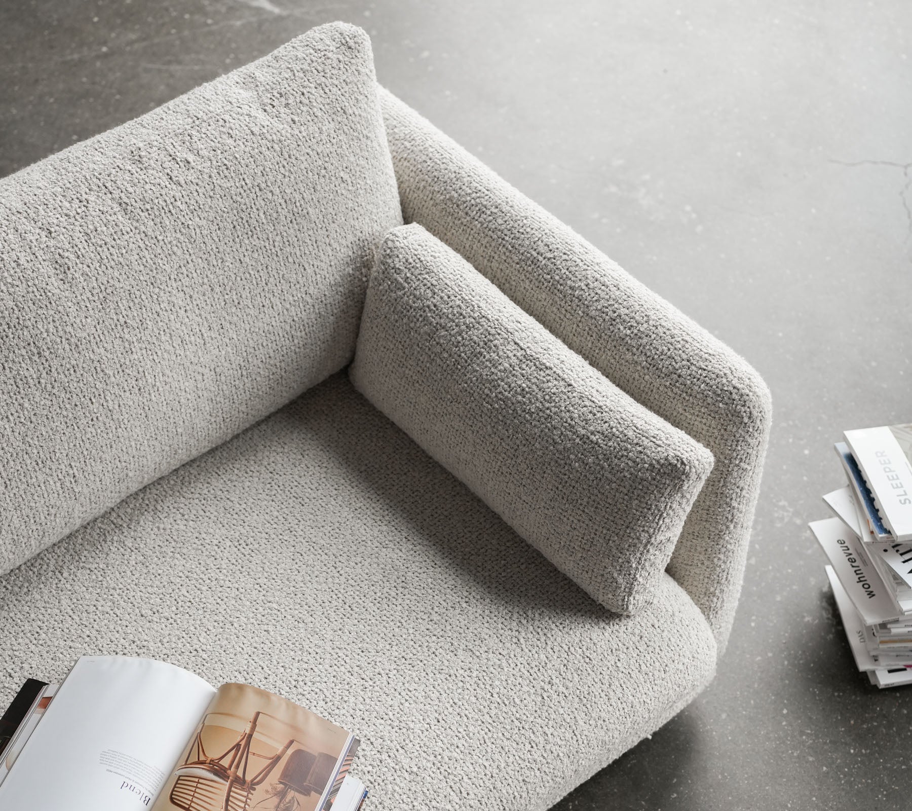 Stylish sofa with a textured surface, featuring a plush armrest and a comfortable cushion, perfect for relaxing and reading.
