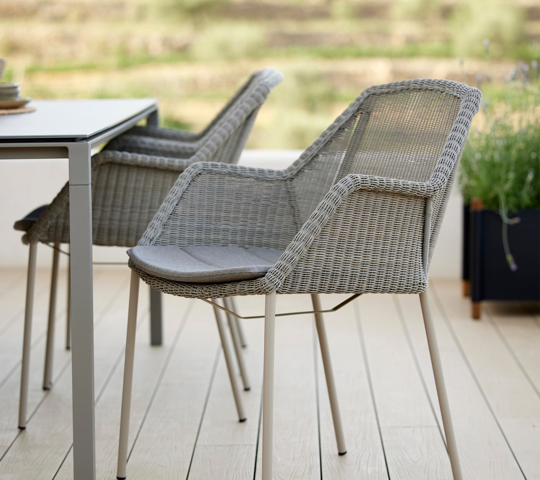 Two stylish woven chairs beside a modern table, featuring a sleek design and comfortable cushions, ideal for relaxation in a serene setting.