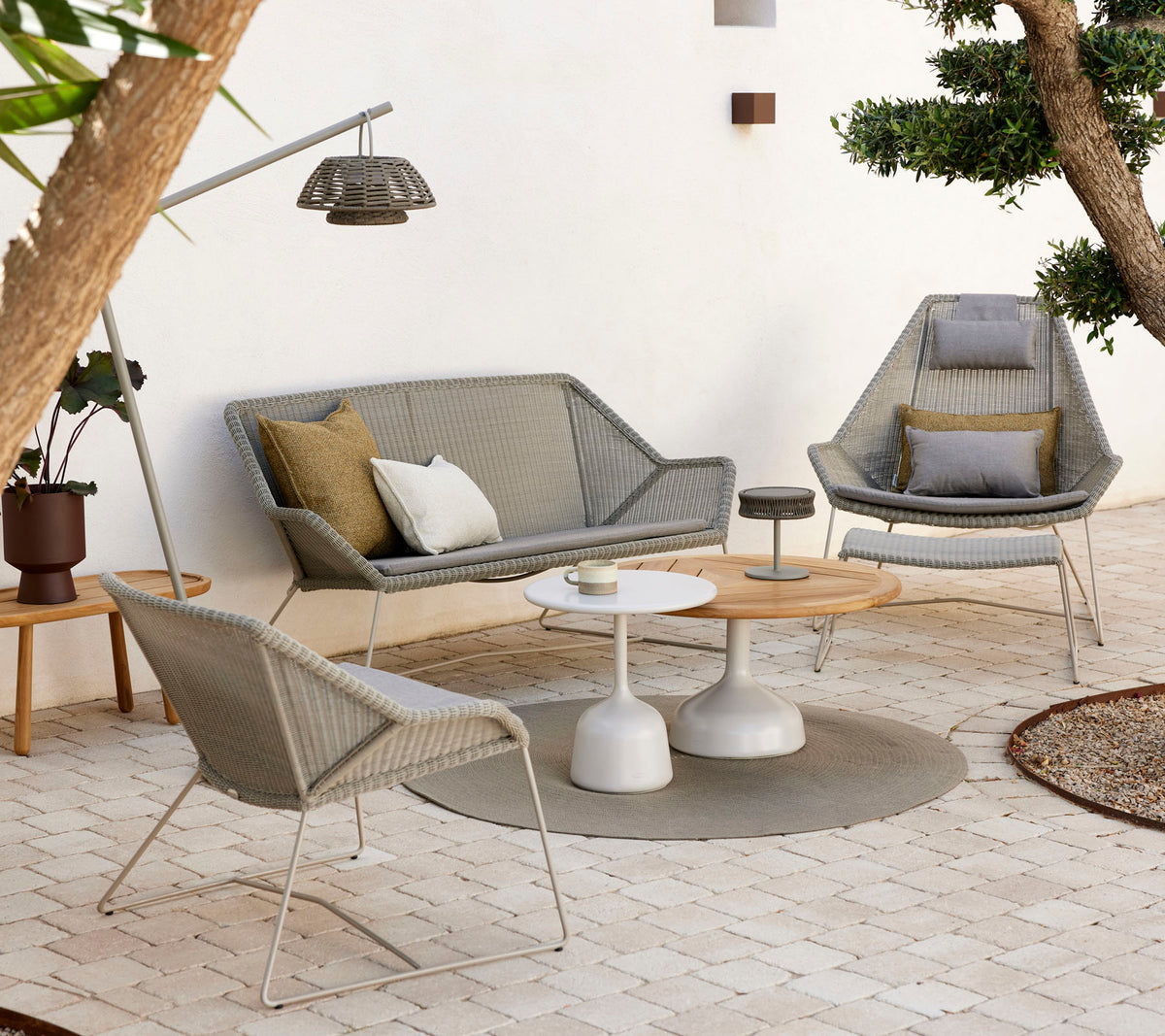 Stylish lounge seating with a coffee table, featuring textured cushions and natural tones, surrounded by greenery and gentle lighting.