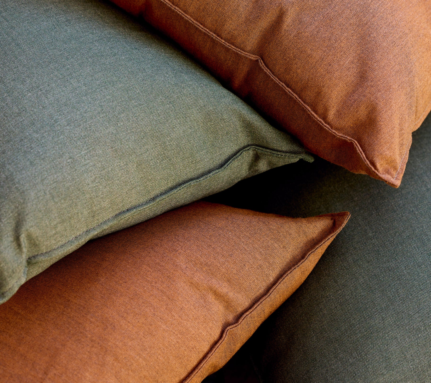 Stack of green and brown cushions arranged together.