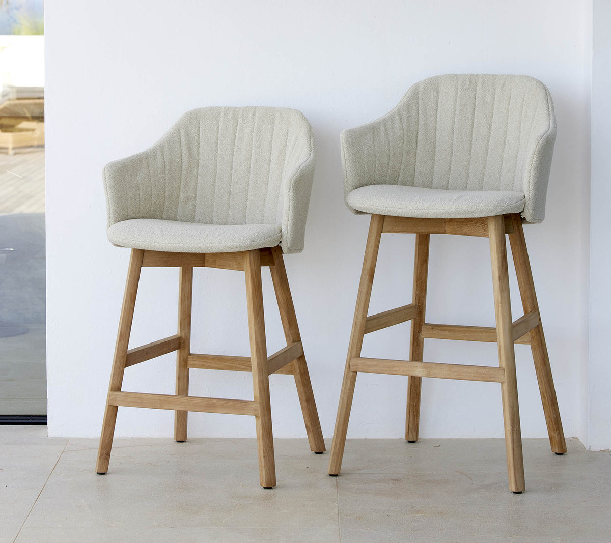 Two stylish, light-colored chairs with curved backs and wooden legs, showcasing a modern and comfortable design.