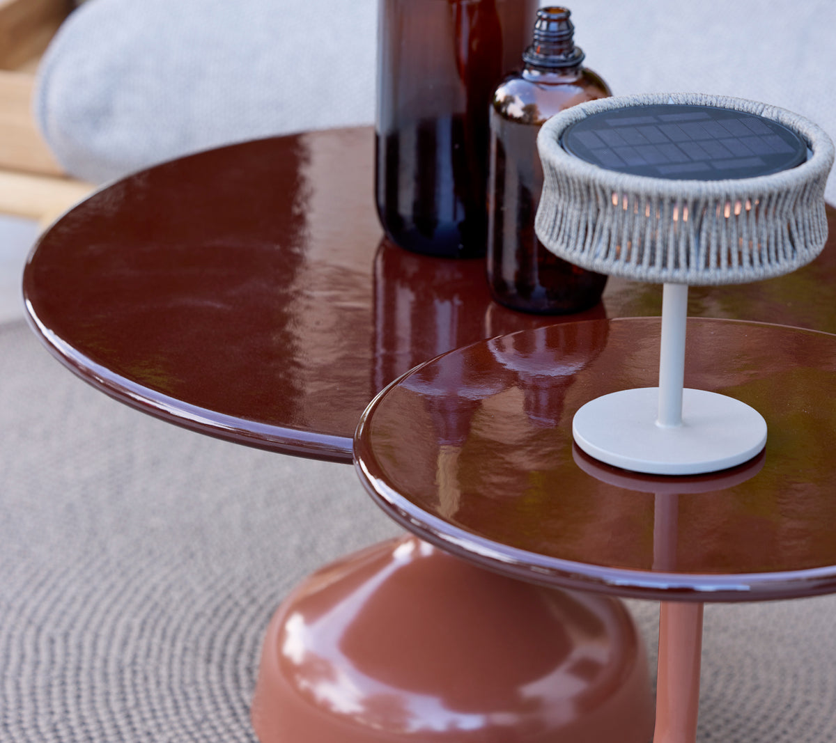 Modern brown table with a white lamp and bottles on a textured surface.