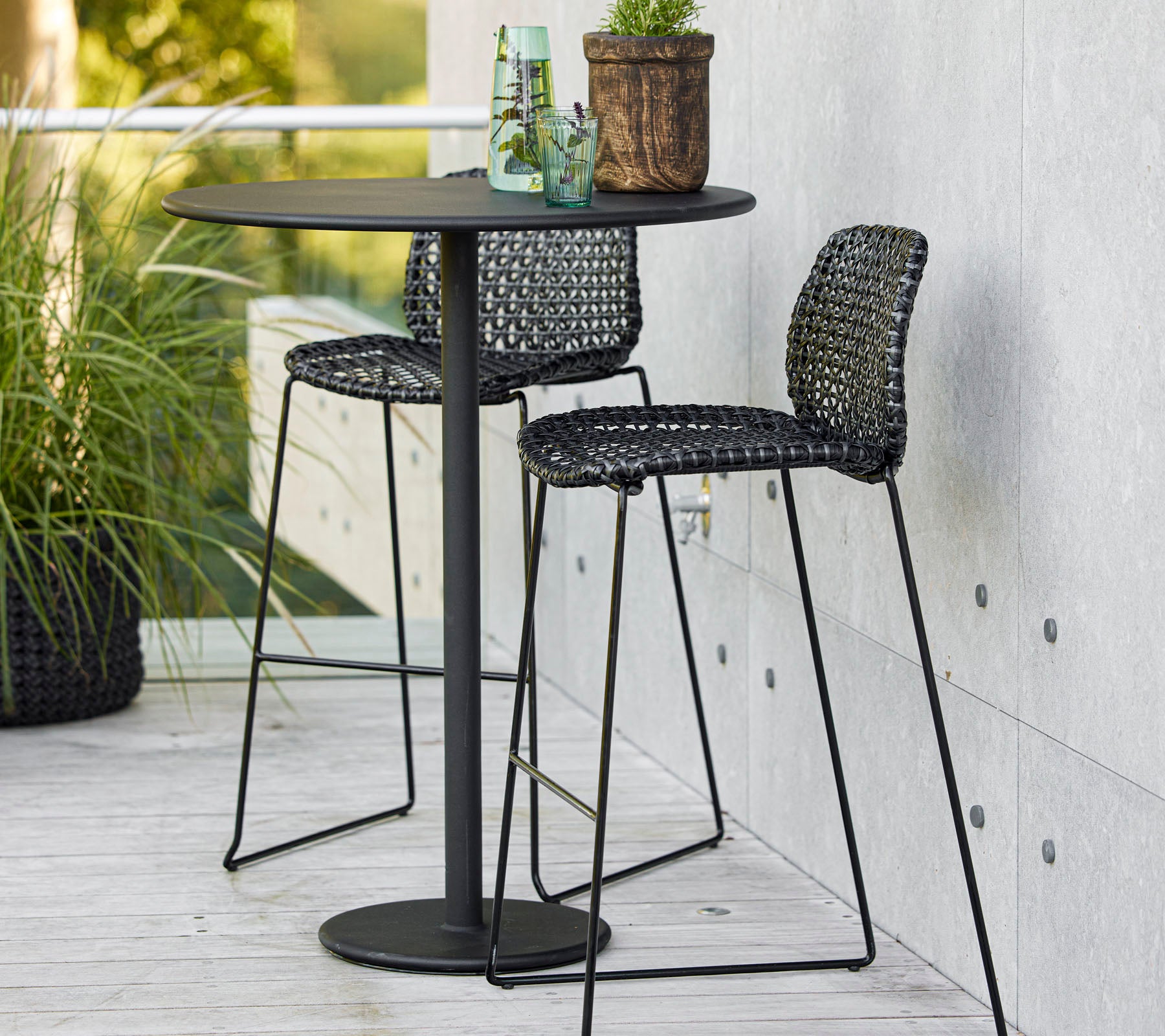 Stylish bar set featuring a round table and two woven bar chairs, perfect for setting a vibrant social vibe.