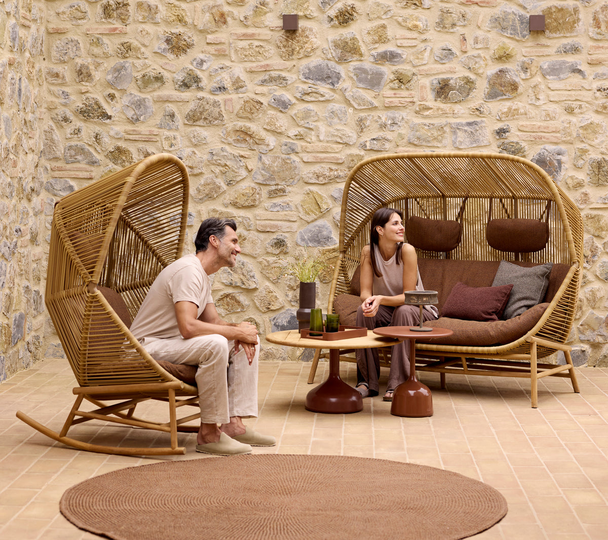 Two people relax on stylish Hive rocking chairs and a Hive sofa, surrounded by Glaze coffee tables and a soft knit rug.