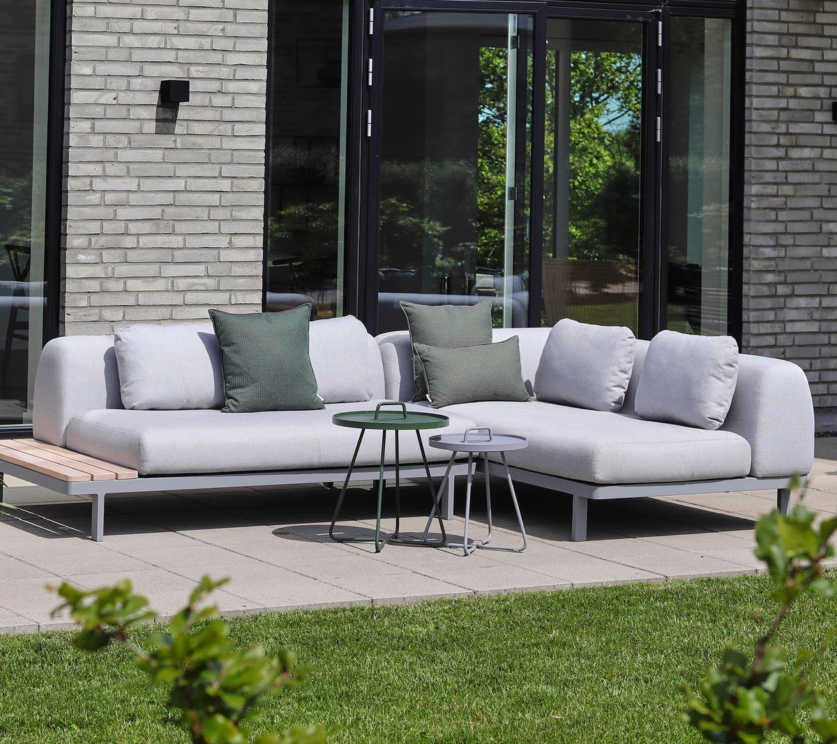 Modern sectional sofa in light fabric with decorative pillows, paired with small side tables in a tranquil setting.