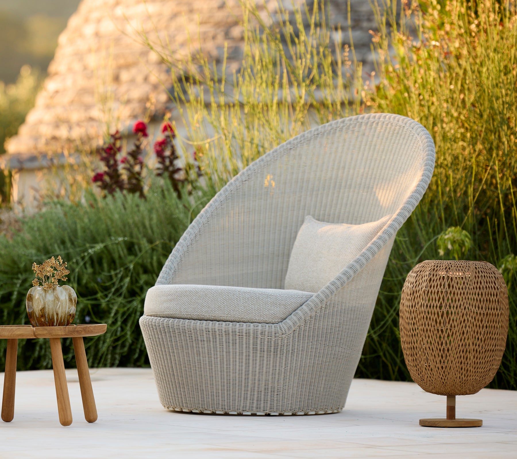 Modern grey chair with cushion and brown table in a natural outdoor setting.