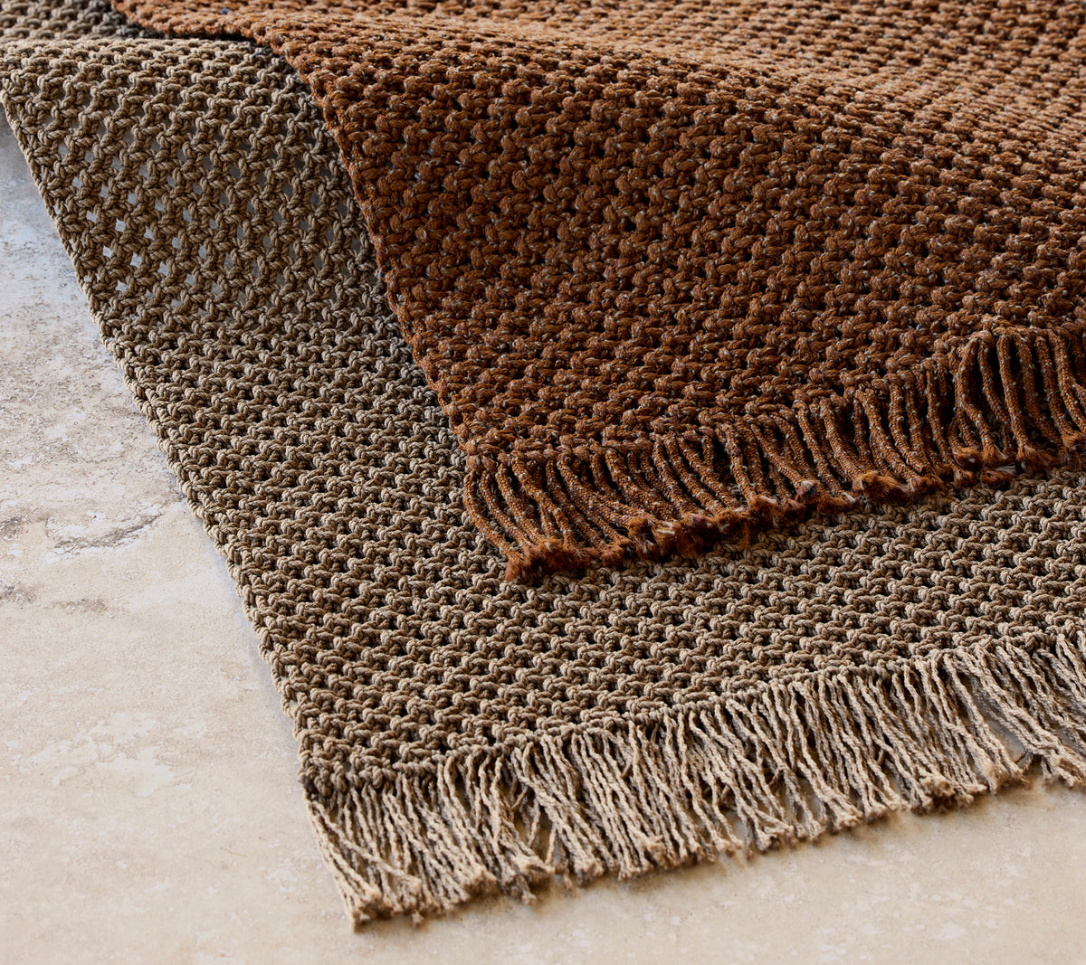 Knit rug measuring 240x170 cm in a textured pattern with fringed edges, featuring warm brown tones.