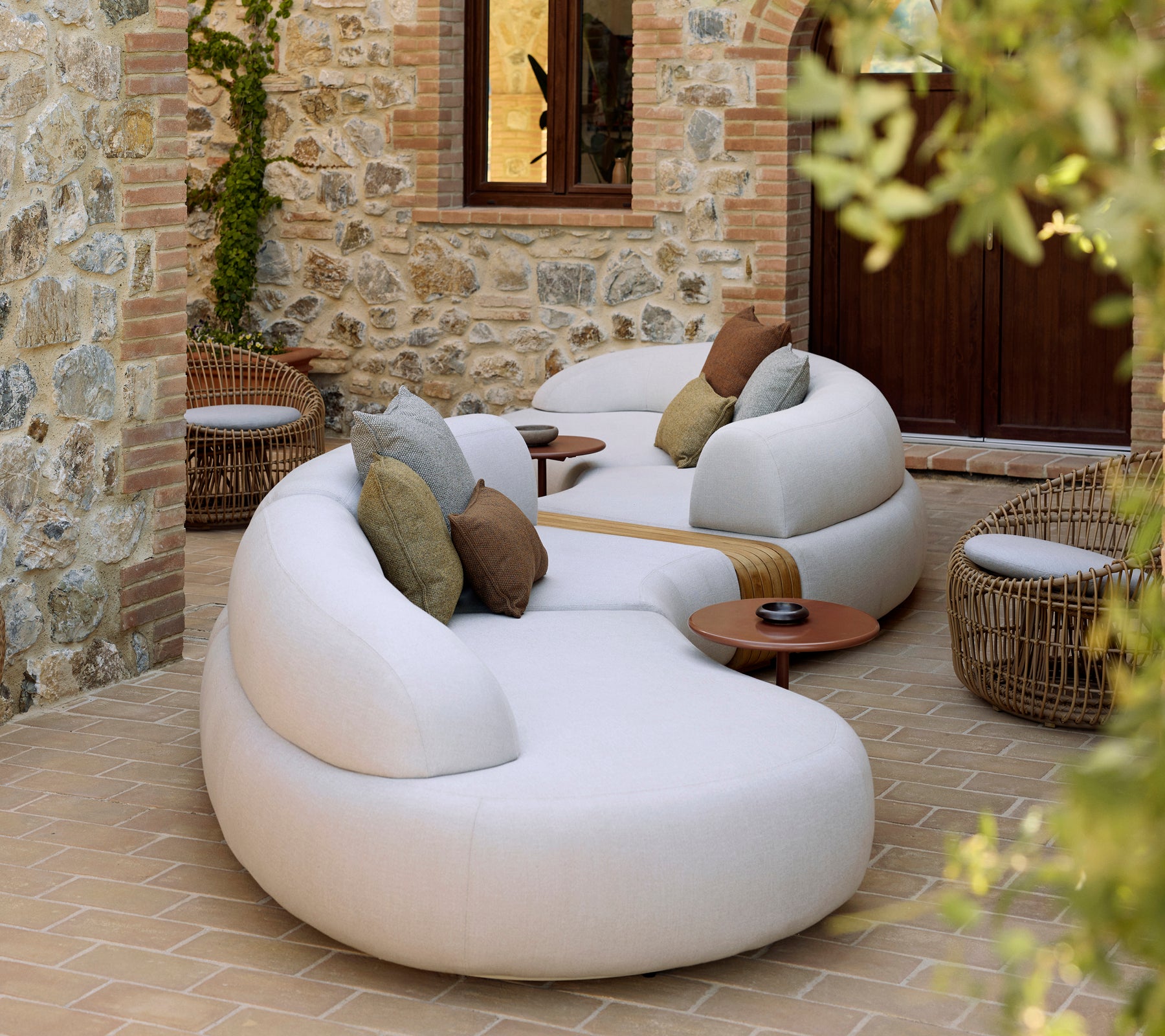 Mellow lounge featuring a Nest round chair and Glaze coffee table, complemented by decorative pillows in a tranquil setting.