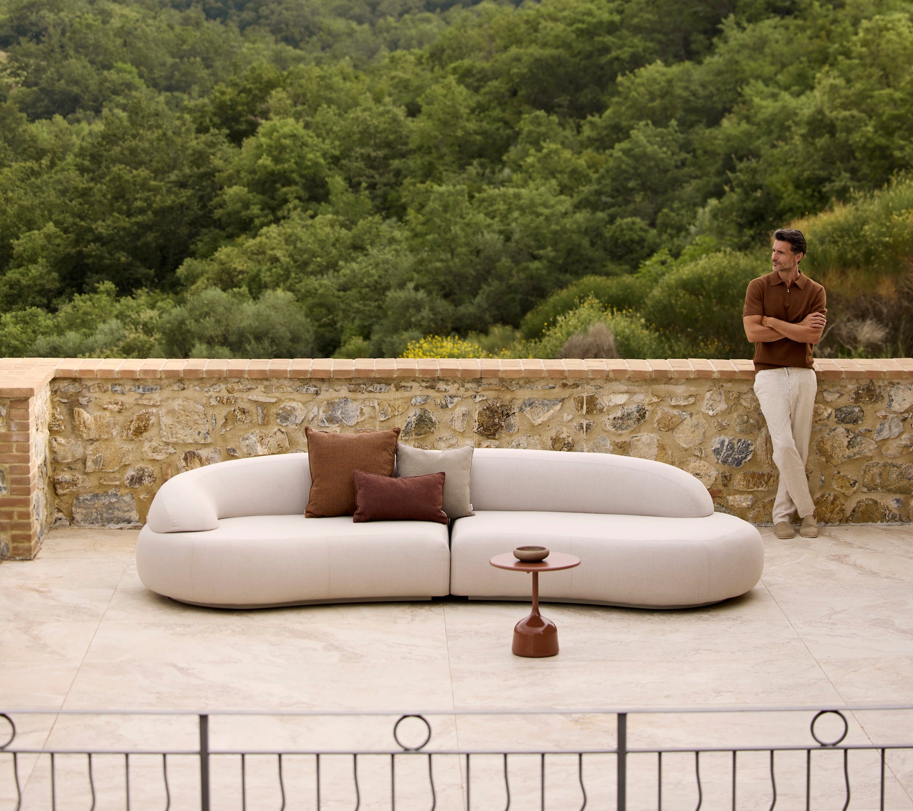 Mellow lounge sofa with Rise cushions and a Glaze coffee table, set against a lush green backdrop.