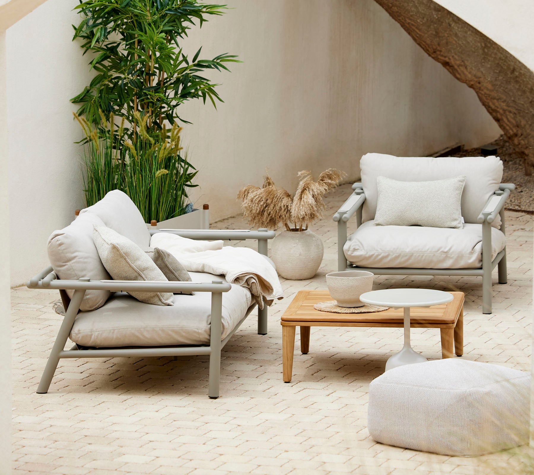 Cozy seating arrangement with plush cushions, a wooden coffee table, and decorative elements, surrounded by greenery.