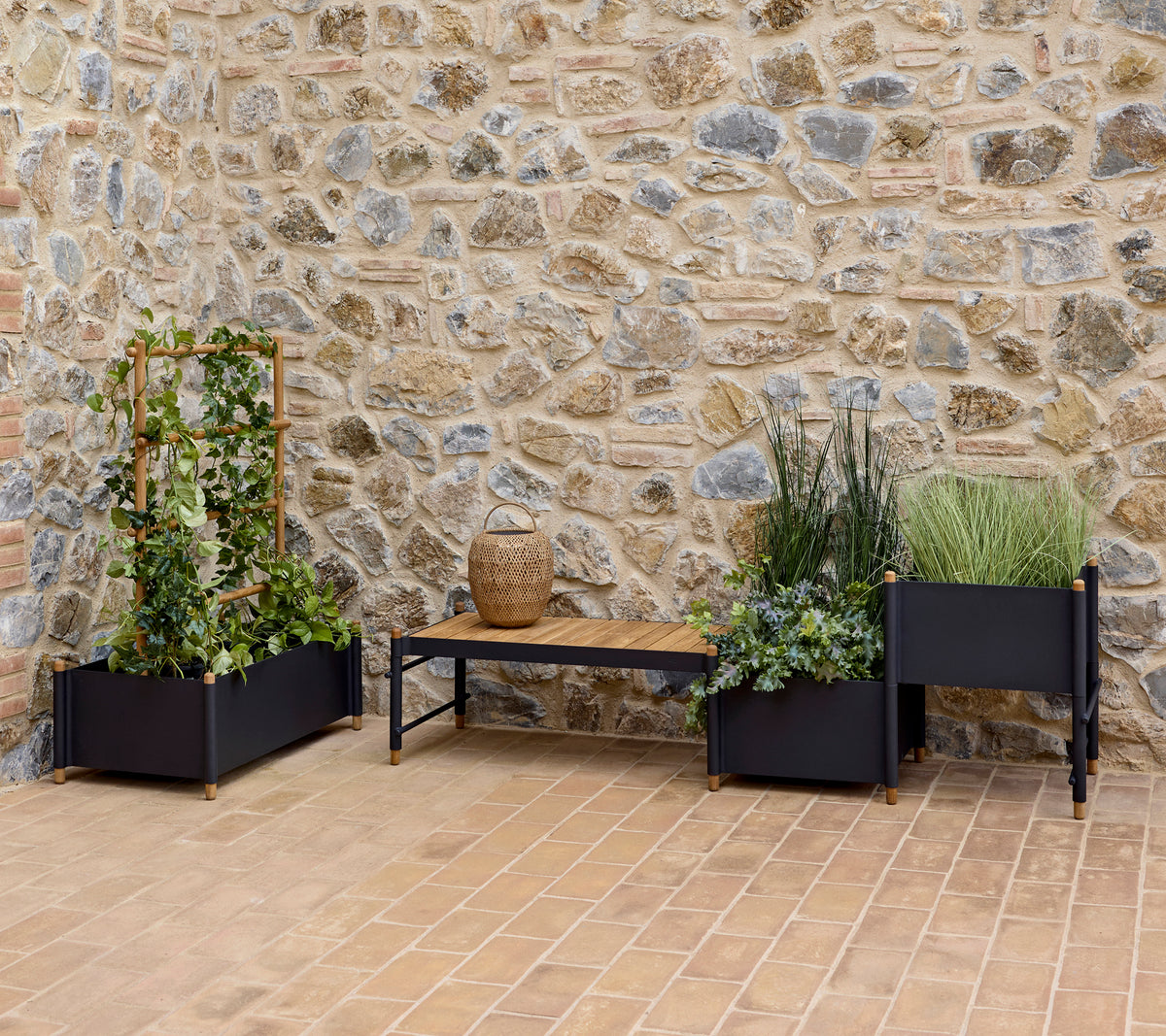 Stylish planters with lush greenery and a bench, set against a textured stone wall, enhancing a serene outdoor space.