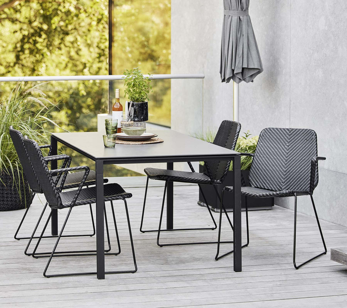A modern table surrounded by stylish chairs, complemented by decorative items and greenery in the background.