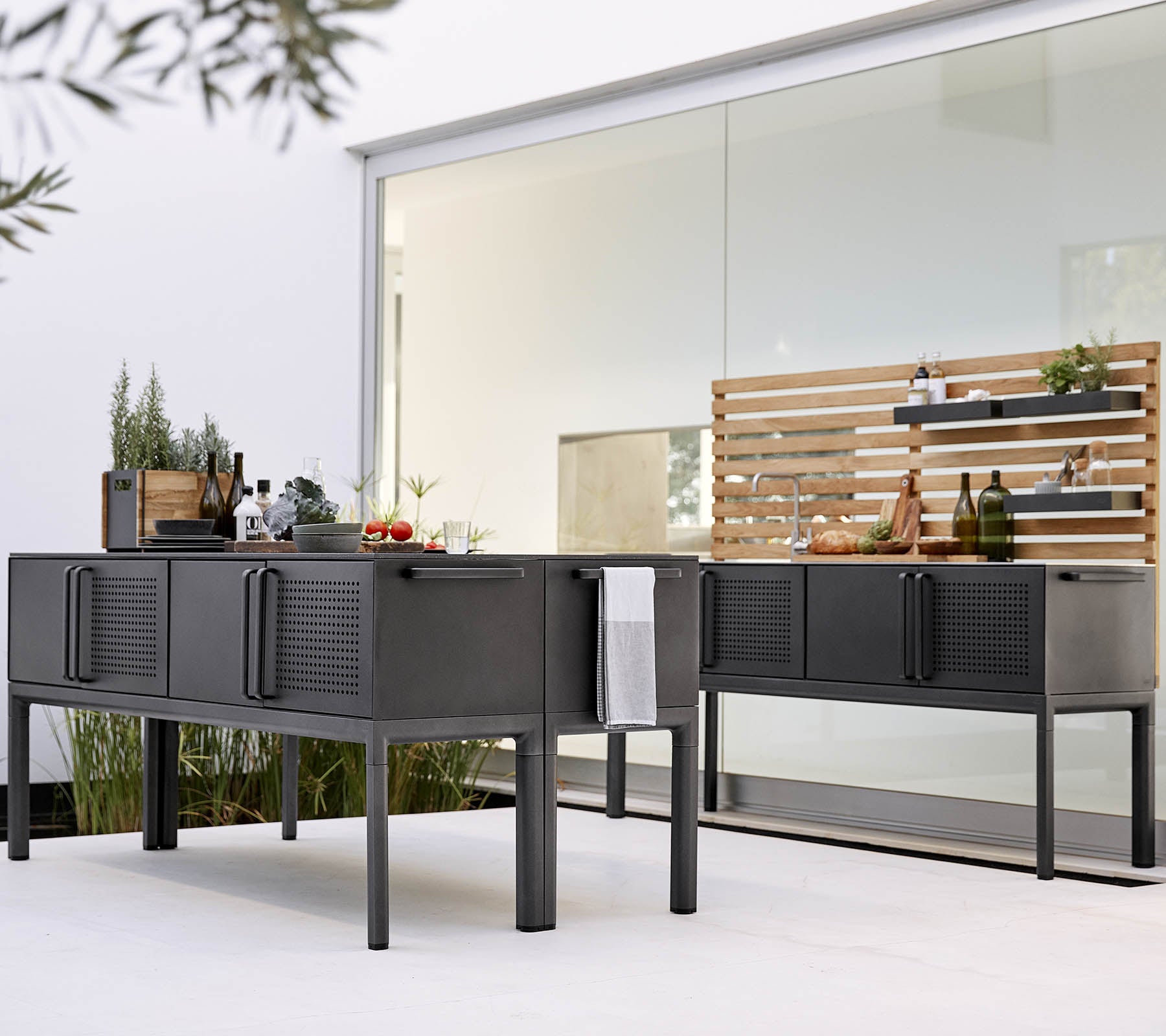 Contemporary outdoor kitchen setup featuring sleek, black cabinetry and a wooden shelving unit for storage and display.